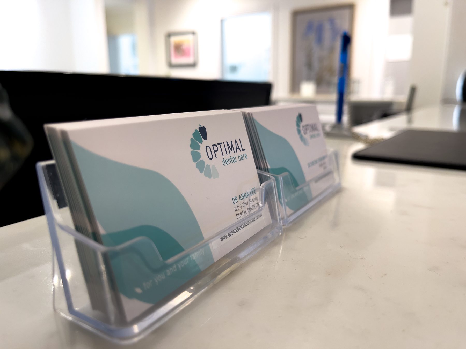Optimal Dental Care business cards in a holder on the reception counter