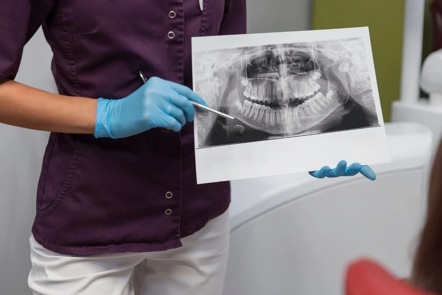 A clinician holding and reviewing a panoramic dental X-ray of a patient’s jaw