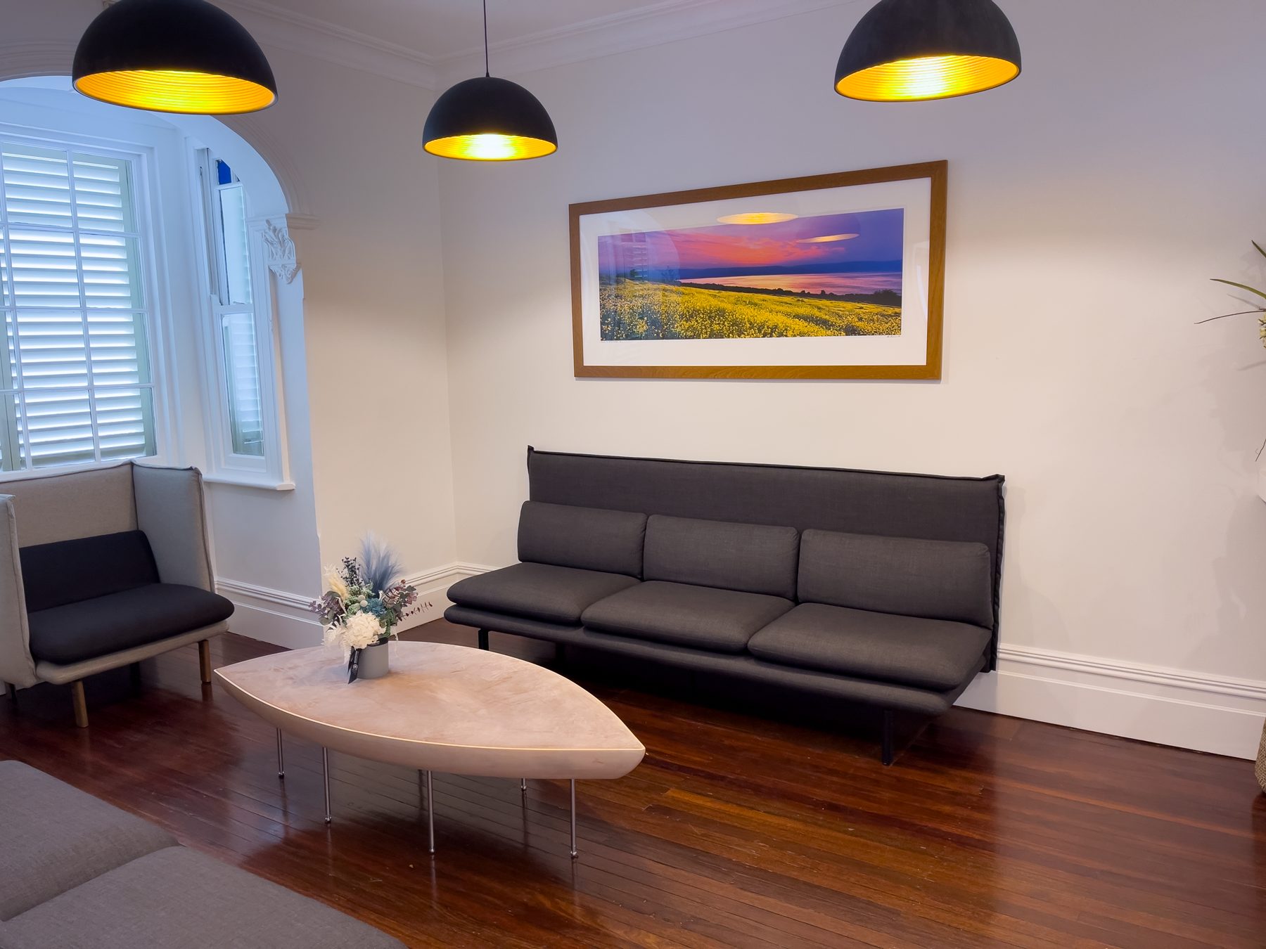 A waiting-room sofa beneath a large framed coastal landscape print at Optimal Dental Care